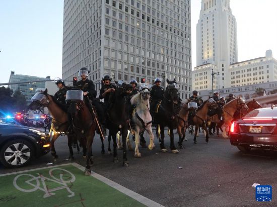 6月10日，在美国加利福尼亚州洛杉矶市中心，骑警在宵禁生效后试图驱散街上的人群。新华社发（邱晨摄）