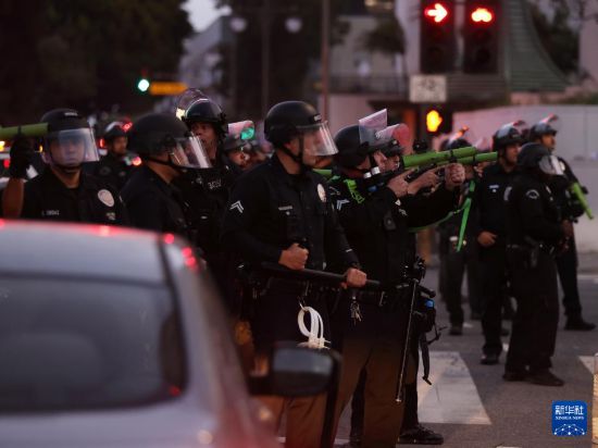 6月10日，在美国加利福尼亚州洛杉矶市中心，警察在宵禁生效后试图驱散街上的人群。新华社发（邱晨摄）