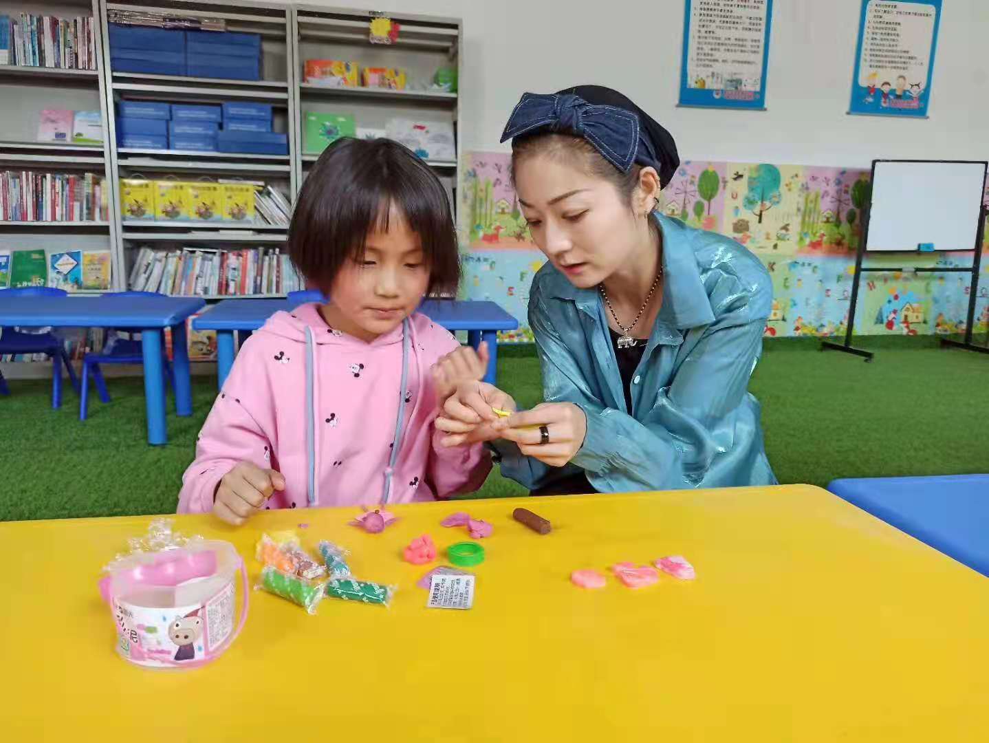 达板镇达板社区童伴妈妈王惠（右）正在陪孩子玩橡皮泥