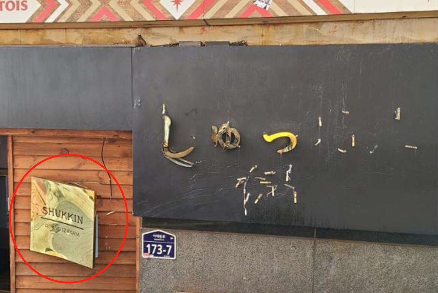 小巷内有店铺挂在墙上的金属招牌被挤掉一半。 图自韩媒