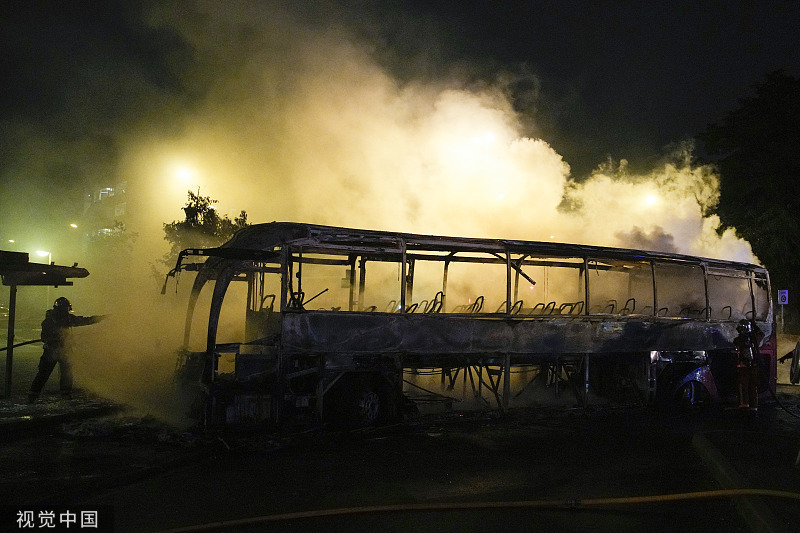 6月30日晚间，骚乱仍在持续。图为消防队员在烧毁的公交车旁灭火。