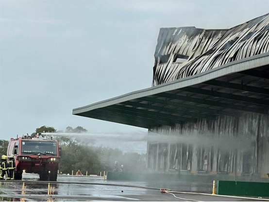 消防人员15日仍在扑灭家乐福仓储火灾余火,拆除建筑过程中释放了燃烧引起的恶臭气体导致附近学校师生不适并紧急停课。图自台湾“中时新闻网”