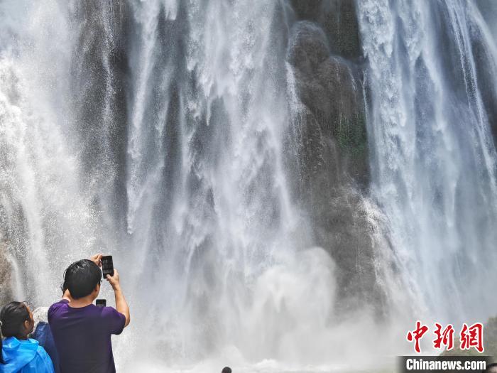 游客在三叠岭瀑布下拍照。陈冠言 摄