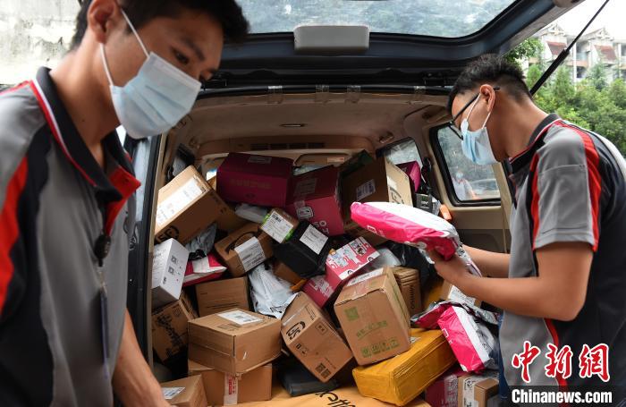 两辆载有近三千件快递的货车停在重庆大学校园内的菜鸟驿站旁等待卸货