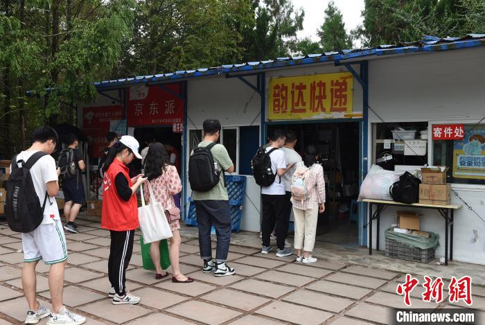 图为两辆载有近三千件快递的货车停在重庆大学校园内的菜鸟驿站旁