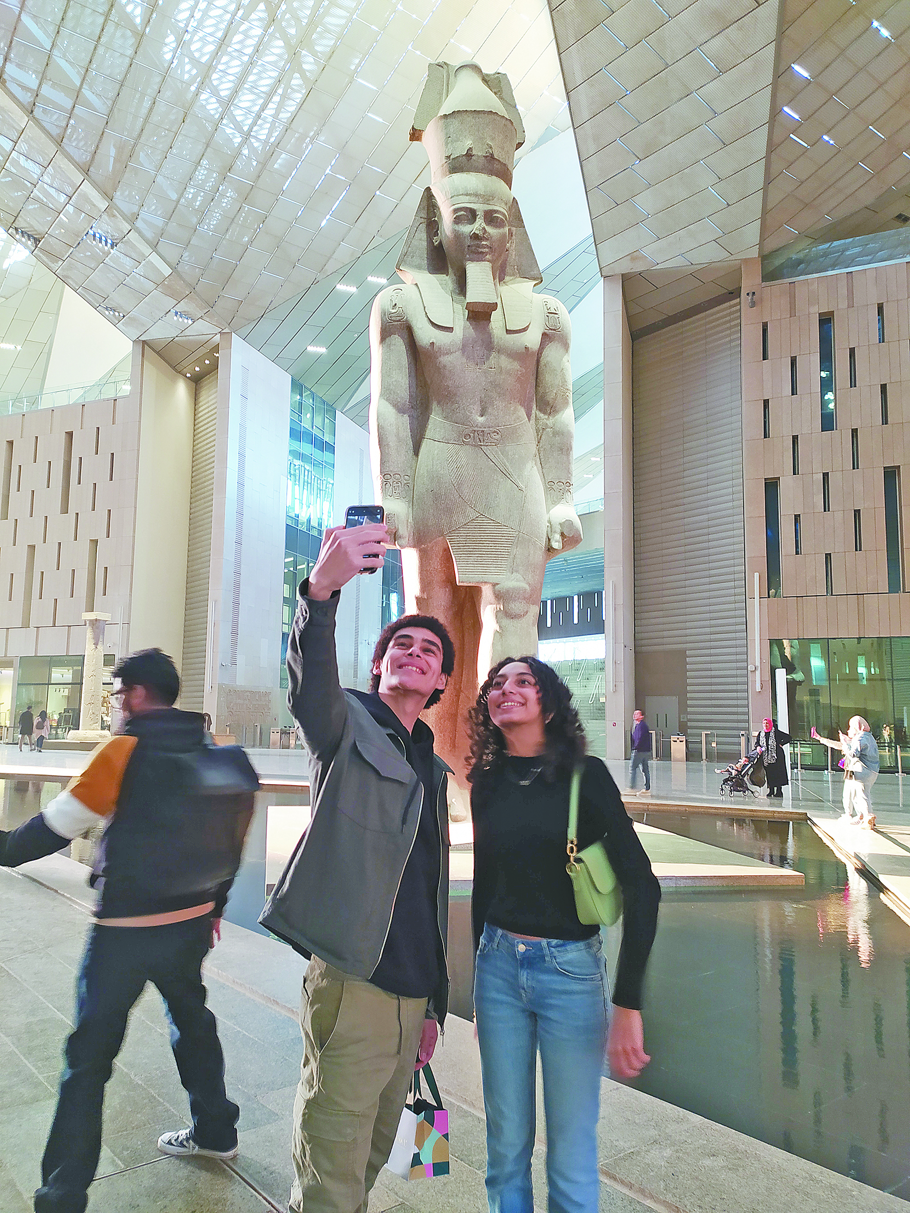 人们在博物馆大厅的拉美西斯二世巨型雕像前拍照。