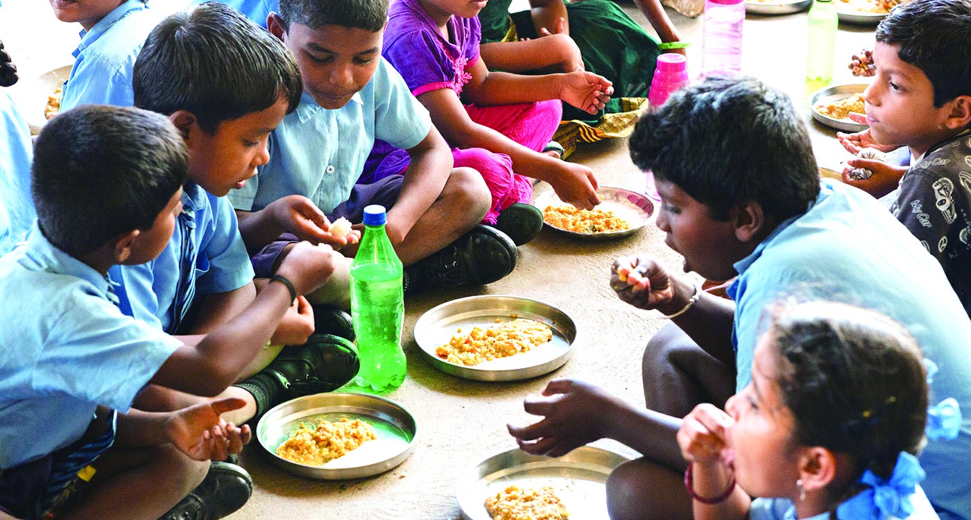 图为印度小学生在食用小米加工的营养午餐.