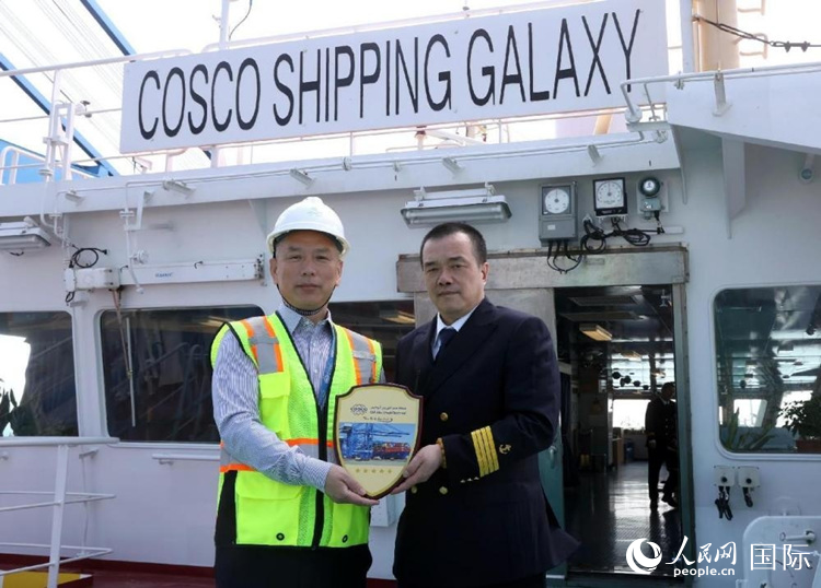 中远海运港口阿布扎比码头有限公司总经理陈玉平（左）登上“中远海运银河”轮，向船员表示慰问，并向船长谢卫国赠送纪念牌。人民网 纳达尔·达乌德摄