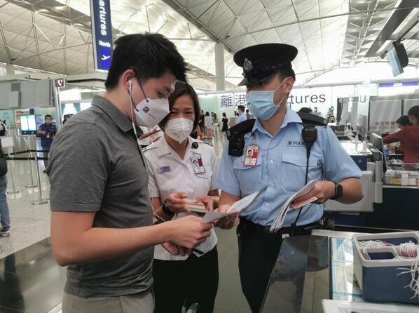 香港警务处和入境事务处人员18日在香港国际机场预办登机柜台派发宣传单，提醒离港旅客小心求职诈骗案及注意外游安全。