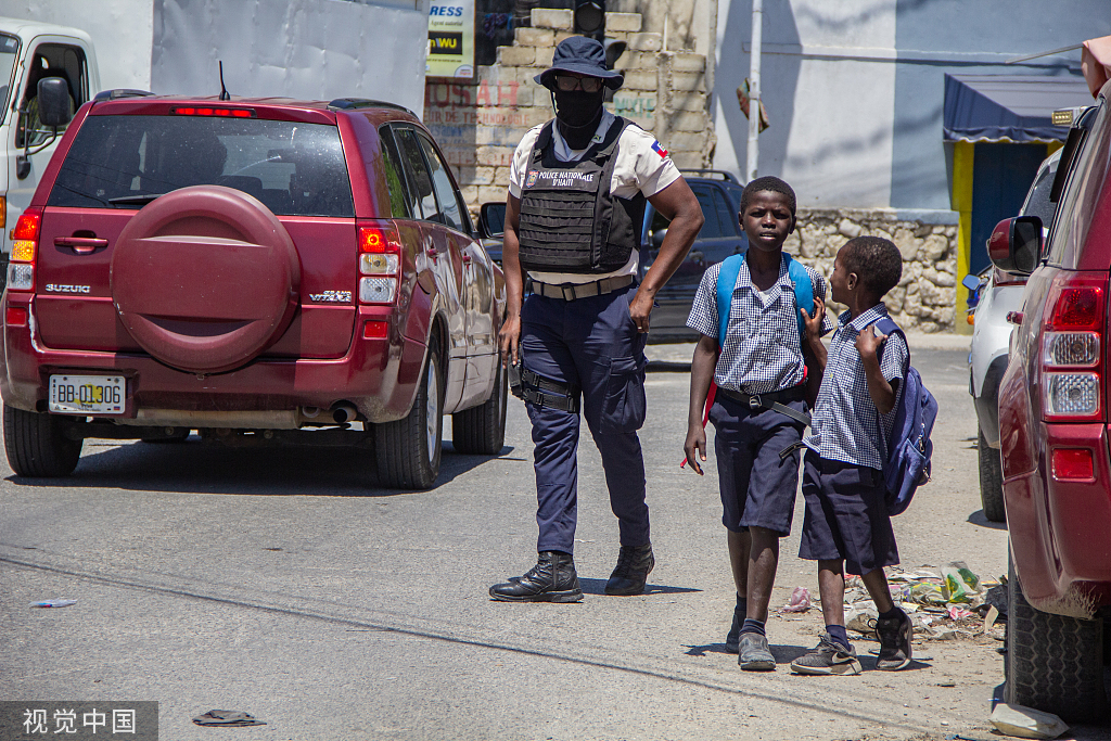 当地时间2023年4月20日,海地太子港,一名警察在市区巡逻,护送学校里的