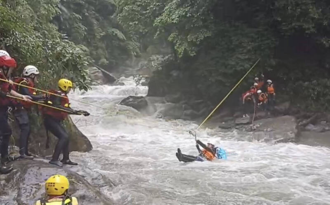 宜兰金岳瀑布溪水暴涨，9人受困对岸，当地消防人员利用绳索横渡救援。图自台媒