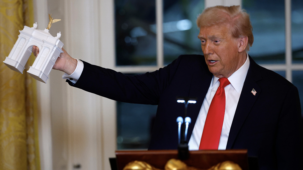 2025年10月15日，特朗普在白宫发表讲话时手持一个拱门模型。图源：美媒