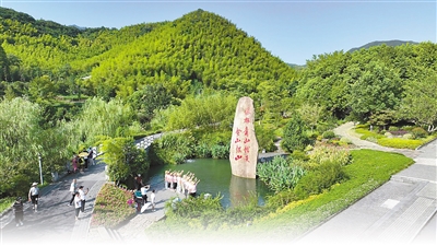 浙江安吉县天荒坪镇余村，游客在镌刻着“绿水青山就是金山银山”的石碑前拍照留念。殷兴华摄
