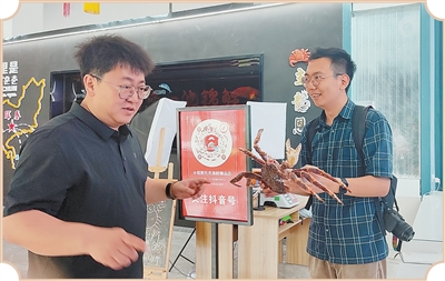 本报记者(右)在帝王蟹展销馆采访。王 旭摄