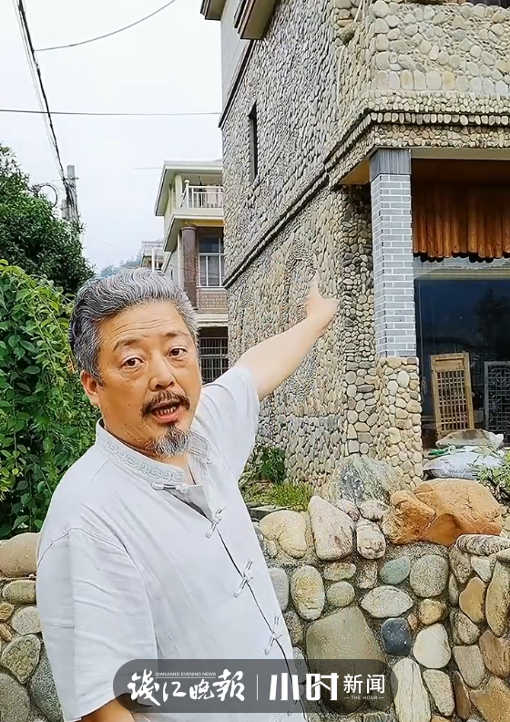 ▲洪新耀正在向人介绍自家的石头房子