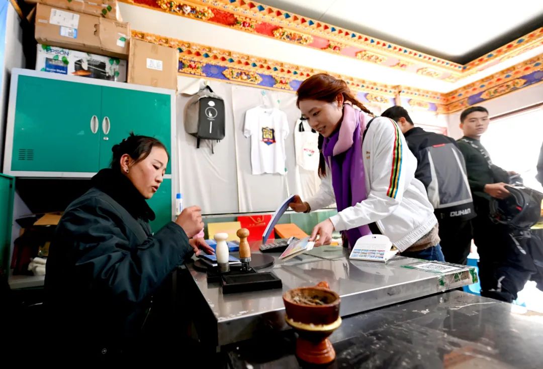 △“天上西藏”邮局珠峰店工作人员措姆正在给游客准备邮寄的明信片盖戳。人民政协报记者 田福良 摄