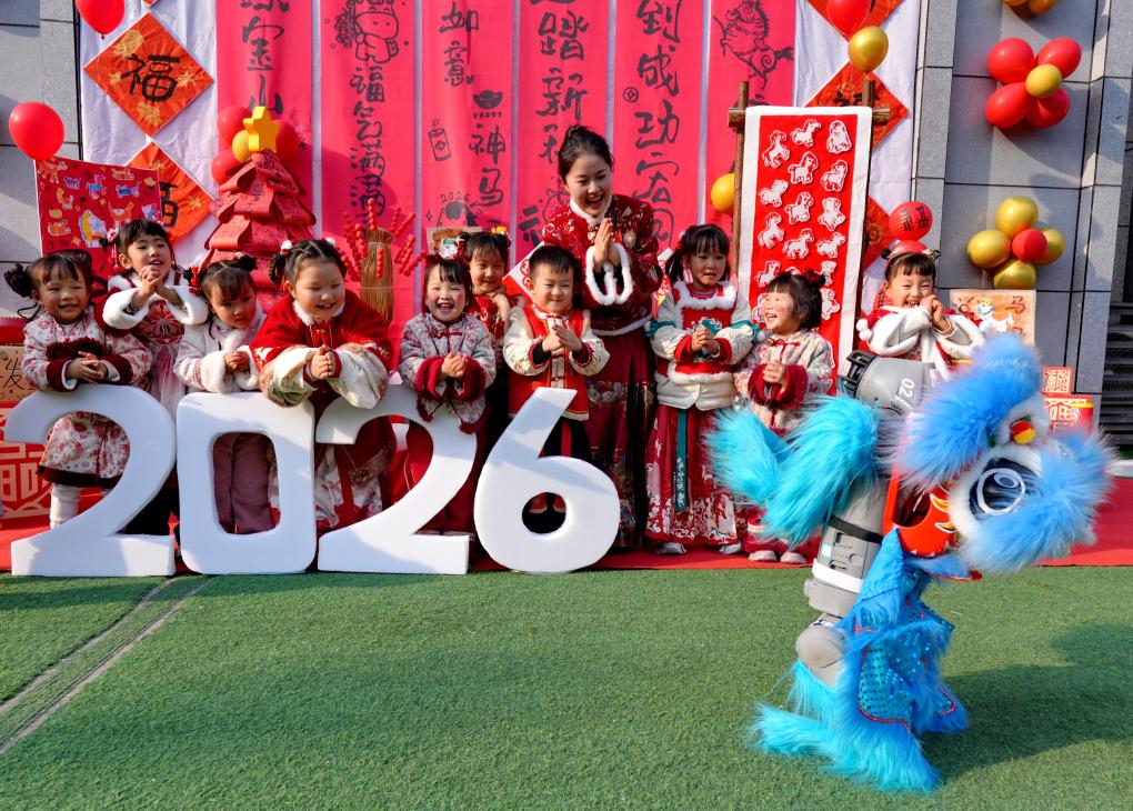 在四川省遂宁市高新区瑰宝明珠幼儿园举办的迎新春非遗庙会上，孩子们和身披舞狮服的机器狗互动（2026年1月14日摄）。新华社发（钟敏 摄）