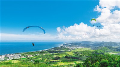 在海南陵水,遊客體驗滑翔傘運動,從空中俯瞰海島美景.