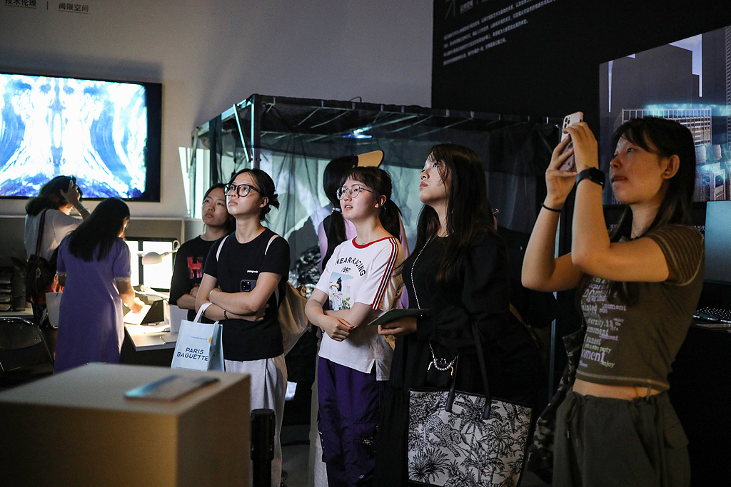 6月,中央美术学院本科生毕业展上,年轻人在观看一件由AI生成的动画作品。(视觉中国)