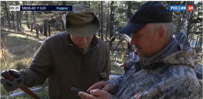普京观看基谢列夫手机中储存的动物活动的视频，图源：“俄罗斯24”电视台视频截图
