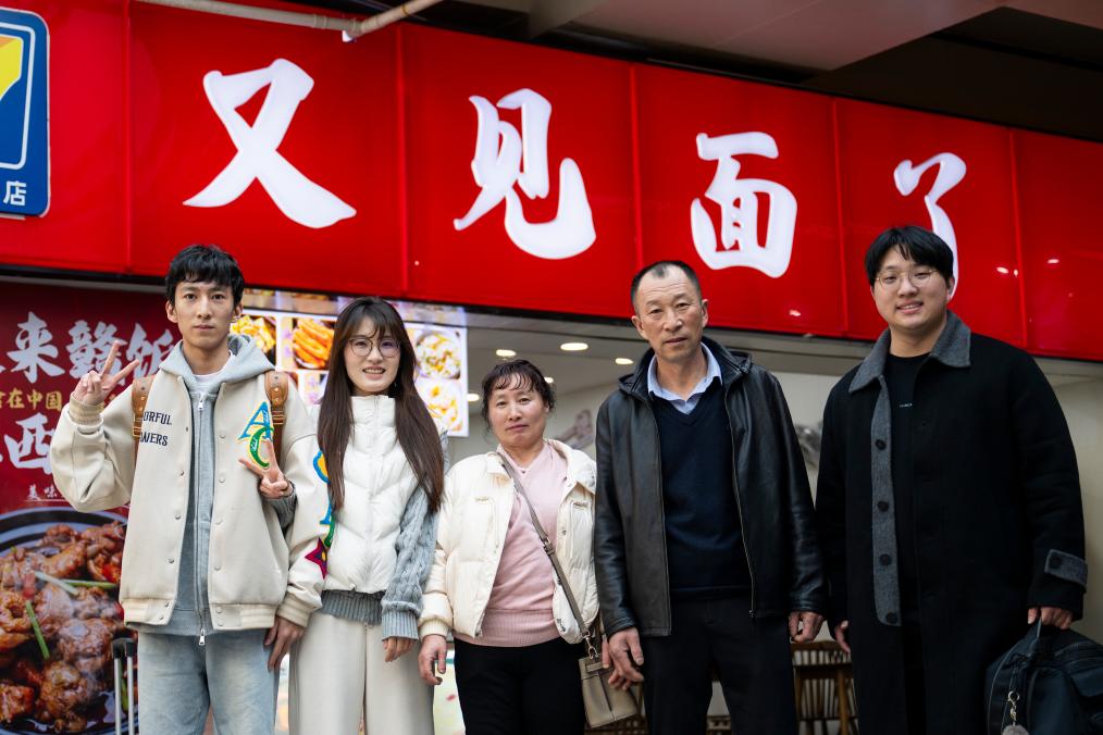 2月14日，在湖北武昌站，王女士（左二）与家人合影。今年王女士的父母和弟弟第一次从吉林珲春来武汉过年。新华社记者 伍志尊 摄