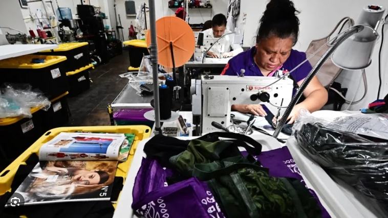 4月18日，美国洛杉矶一家小型缝纫工作室内，工人们正在制衣。图源：法媒