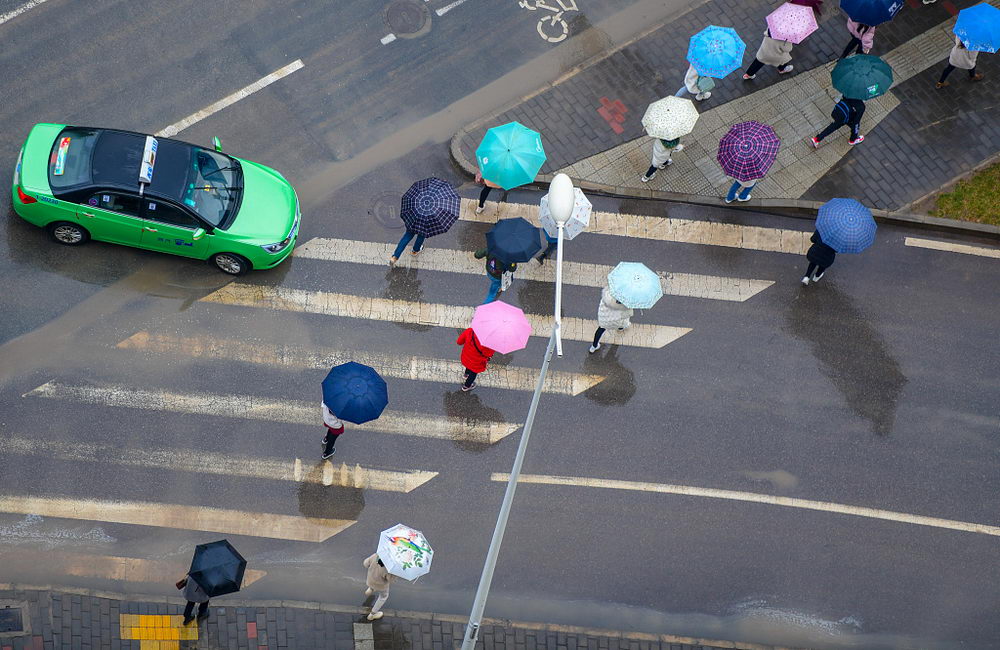 俯瞰西安市南三环公交车站附近行色匆匆的上班族,手中的雨伞相应成趣