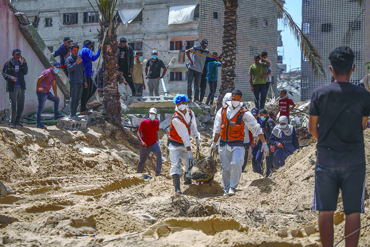 23日，加沙南部汗尤尼斯的纳赛尔医院，民众和医务人员正在挖掘尸体。加沙民防部门称，已在该医院发现近340具尸体。（视觉中国）