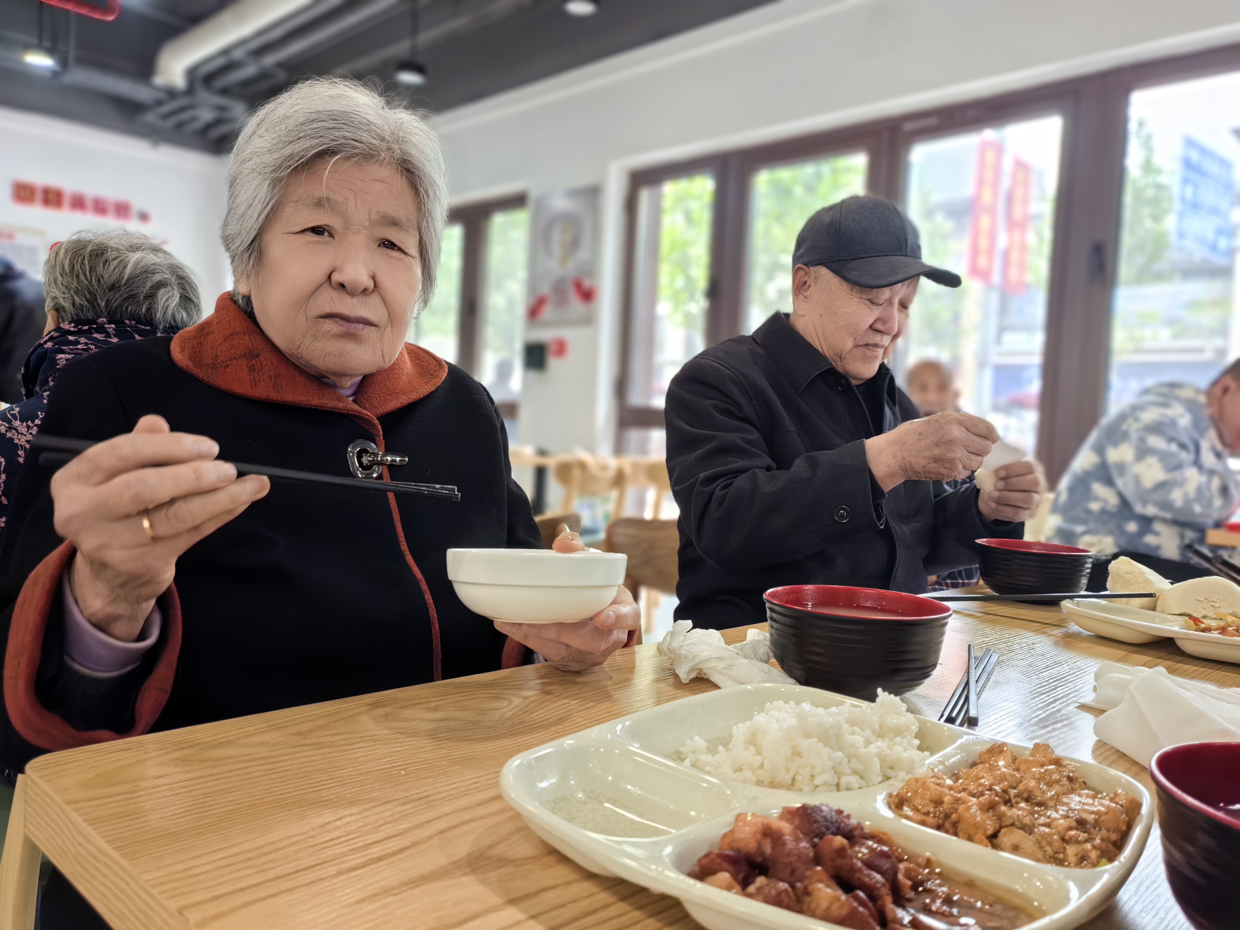 窗明桌净,饭菜飘香,二三十位老年人正在就餐,偶有轻声谈笑