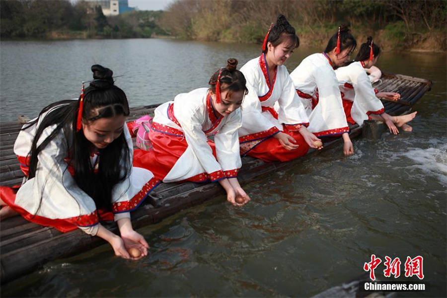 Women wearing traditional Chinese costumes participate in the ancient custom of drifting eggs at Changzhou, Jiangsu province on March 29, 2018. [Photo/Chinanews.com]