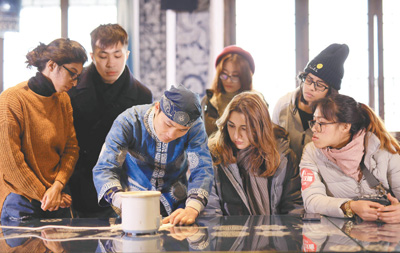 王方周指导游客学习蜡画。黄晓海摄（人民视觉）