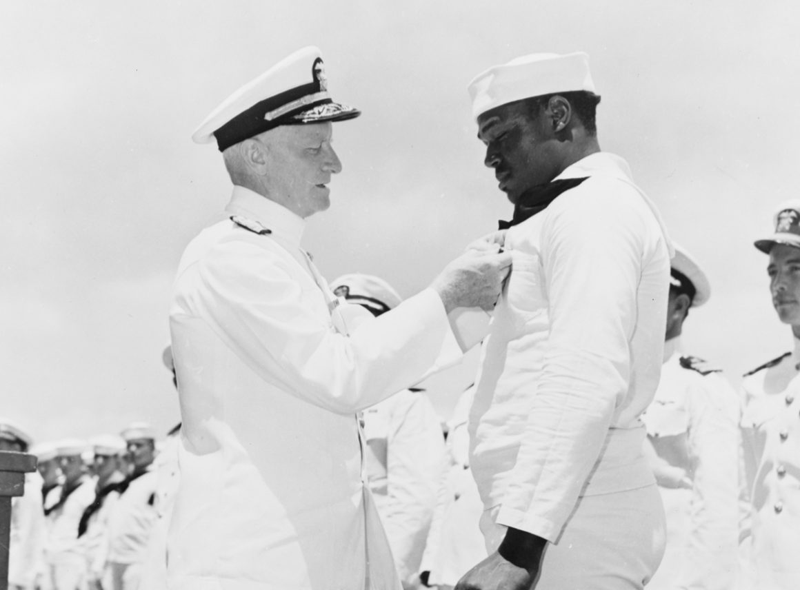 1942年5月美海军上将切斯特·尼米兹在企业号航母CV-6的甲板上，亲自授予米勒海军十字勋章。
