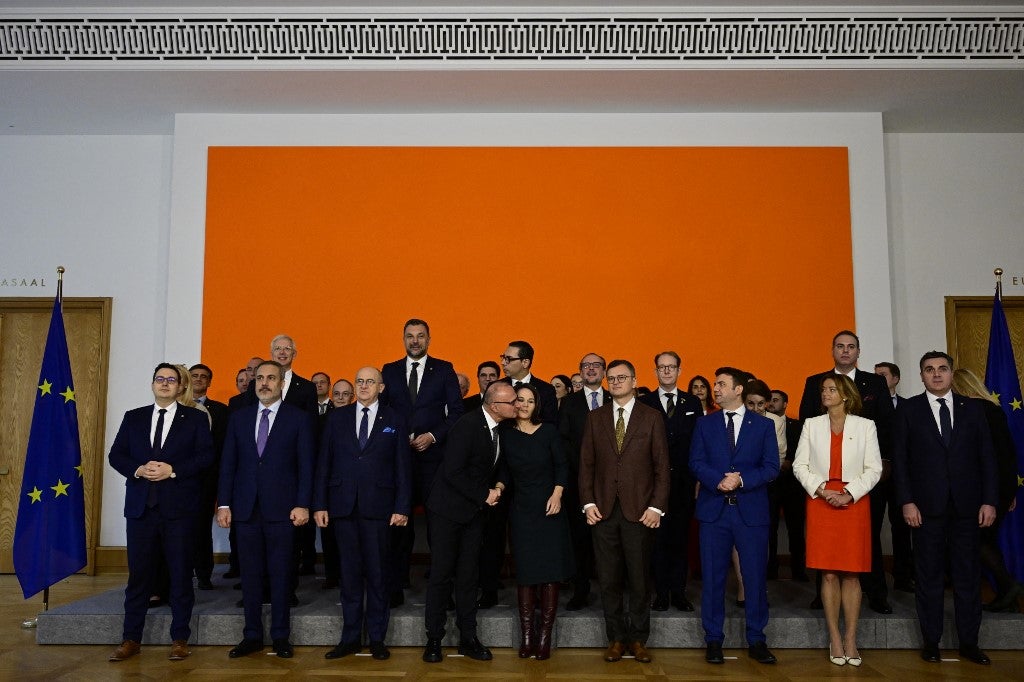 当地时间2日在一次合影中，克罗地亚外长拉德曼试图亲吻德国外长贝尔伯克