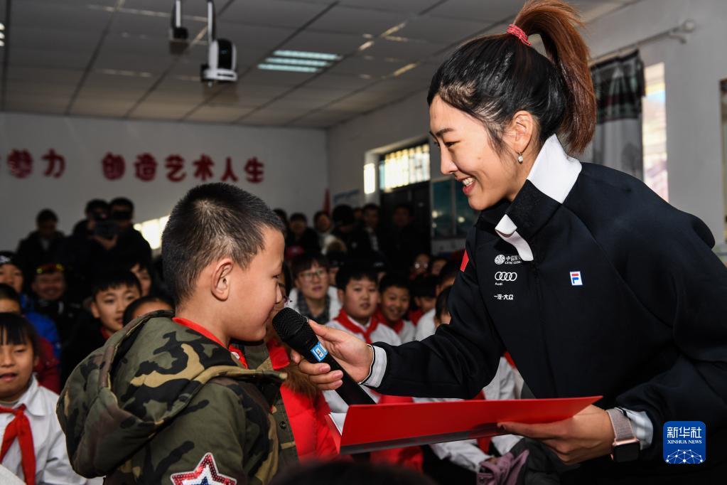 徐梦桃（右）在阿尔山市白狼镇白狼小学与学生进行交流，自由式滑雪空中技巧国家集训队队员利用在内蒙古阿尔山冬训的时间，为当地小学生普及滑雪知识，并给孩子们送去了滑雪板、手套等装备（2018年12月9日摄）。新华社记者 刘磊 摄