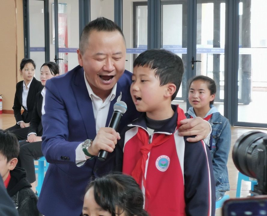 “童心港湾”文化下乡东乡行活动上全总文工团优秀歌手高晓波（左）在教孩子们唱歌