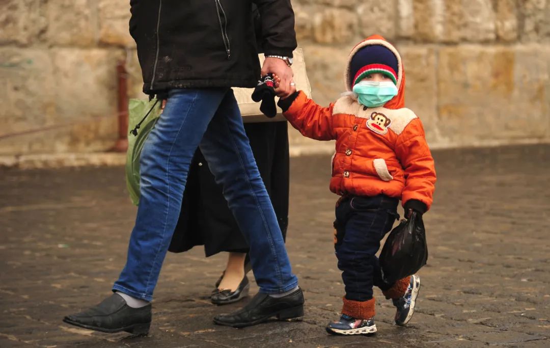 3月21日，在叙利亚首都大马士革，一名男孩戴着口罩在家长的陪伴下出行。新华社发（阿马尔·萨法尔贾拉尼摄）
