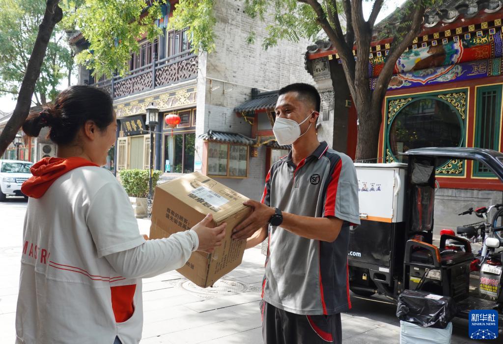 在北京市西城区琉璃厂东街，刘阔把快递送到客户手中（2022年6月25日摄）。新华社记者 陈旭 摄