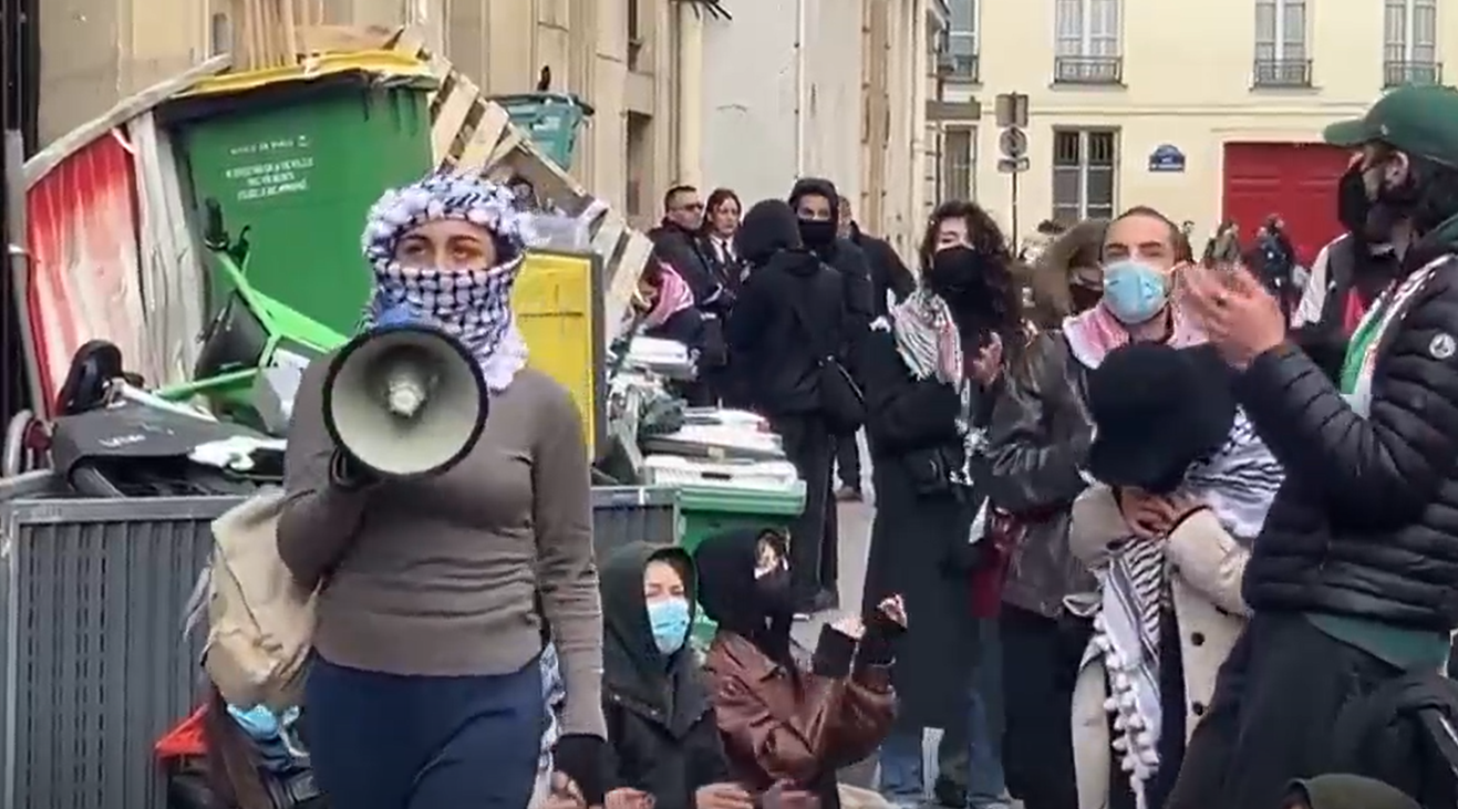 综合美联社、CNN等多家媒体报道，巴黎政治学院位于巴黎市中心的一个校区发生亲巴勒斯坦抗议活动，有抗议者高喊支持巴勒斯坦的口号。此外，该校区一栋楼的入口被垃圾桶、自行车等挡住。图为抗议现场画面。图源：美媒视频截图