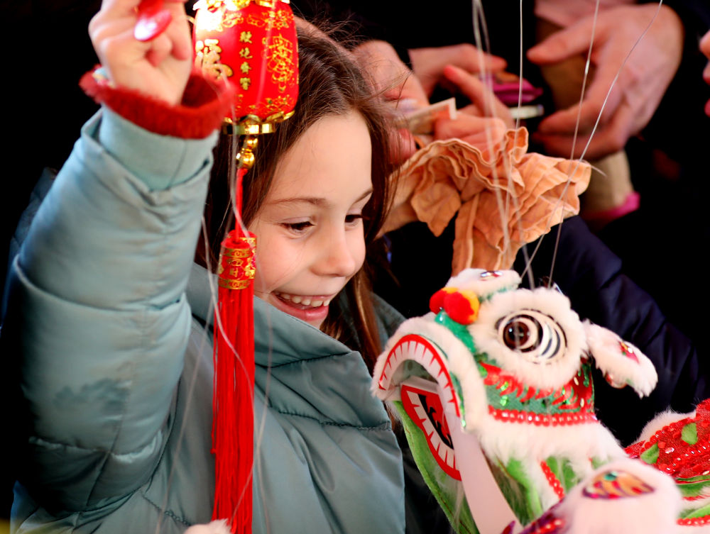 2023年1月22日，一名女孩在英国伦敦特拉法加广场购买提线狮子。特拉法加广场当日举行春节庆典，庆祝兔年新春佳节。新华社记者 李颖 摄