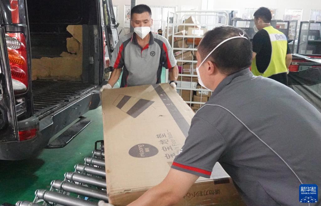 在北京市西城区陶然亭街道一处顺丰速运营业点，刘阔（左）和同事一起将货物装车（2022年6月25日摄）。新华社记者 陈旭 摄