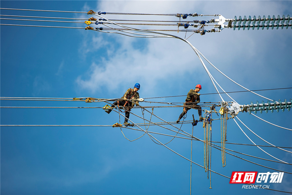 电力工人在高空铺设安全保护网,为安全架线做准备.