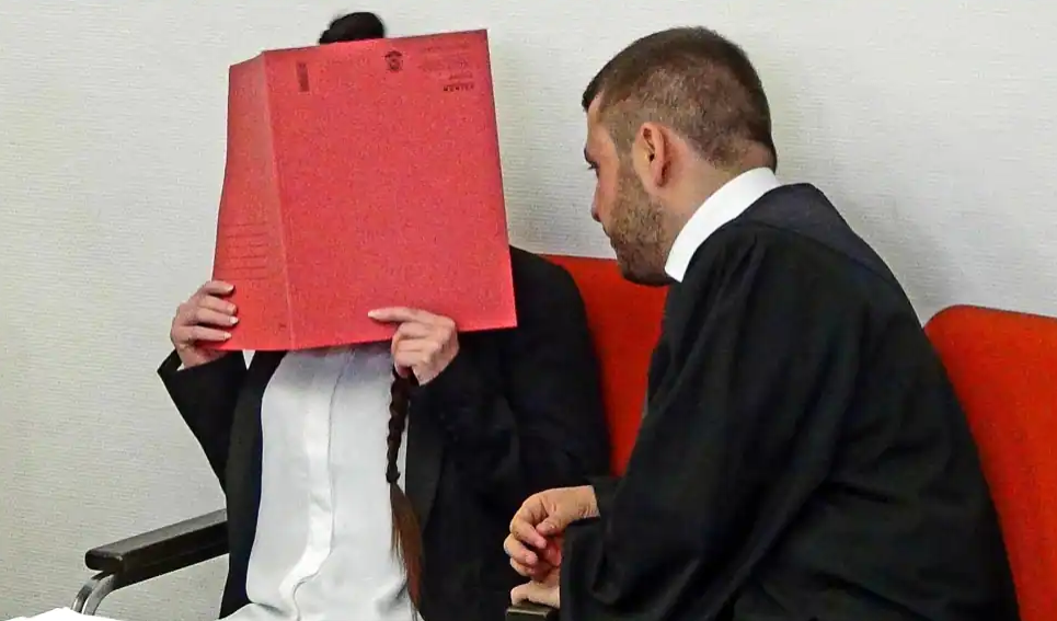 “珍妮佛·W”遮住脸，在律师陪同下等待法院审判。图自 美媒