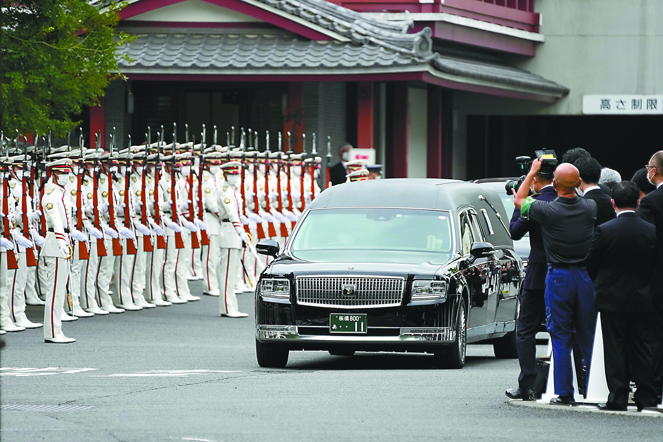 12日,载有安倍遗体的灵车在仪仗队和随从之间穿过.(视觉中国)