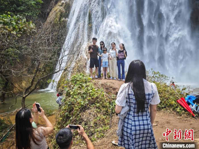 游客在三叠岭瀑布下拍照。陈冠言 摄