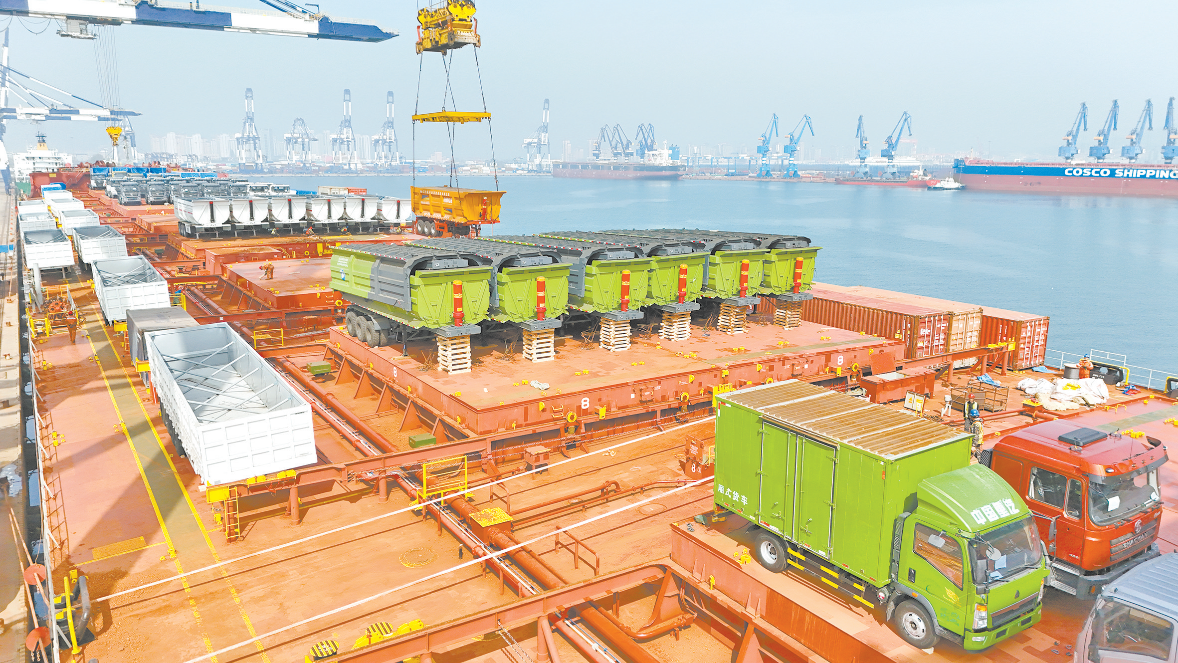 14日，出口几内亚的卡车在山东烟台港装入中非班轮。（视觉中国）