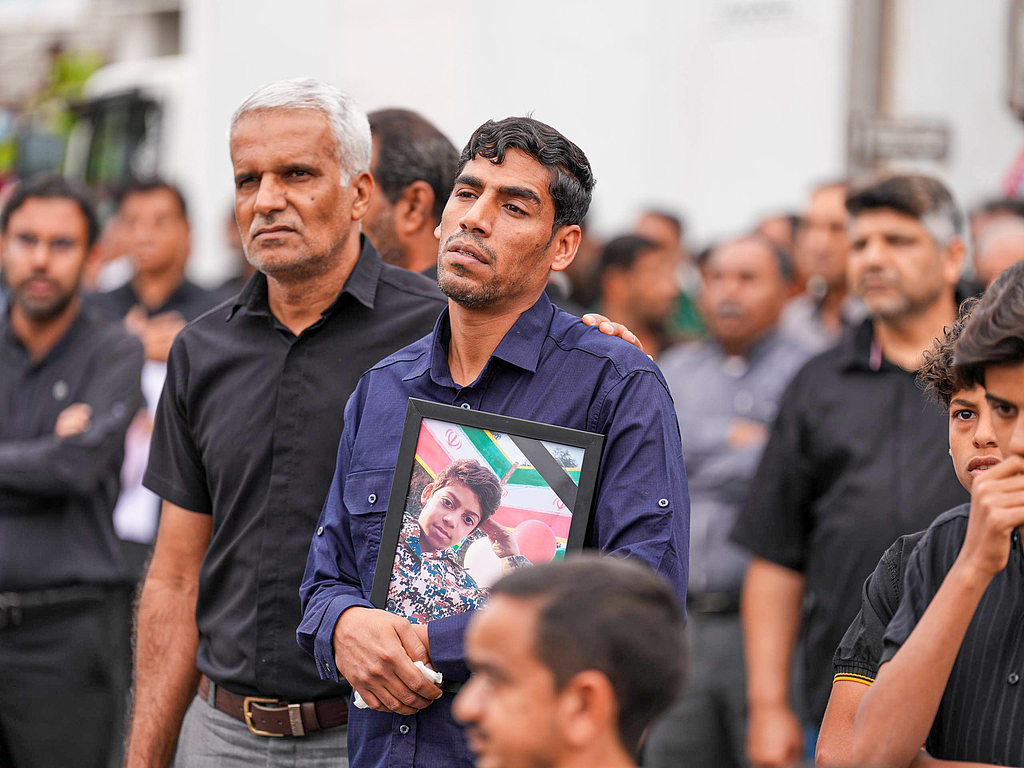 3 日，在米纳卜市举行的葬礼上，哀悼者手捧遗像，悼念在美以袭击中丧生的小学生。（视觉中国）