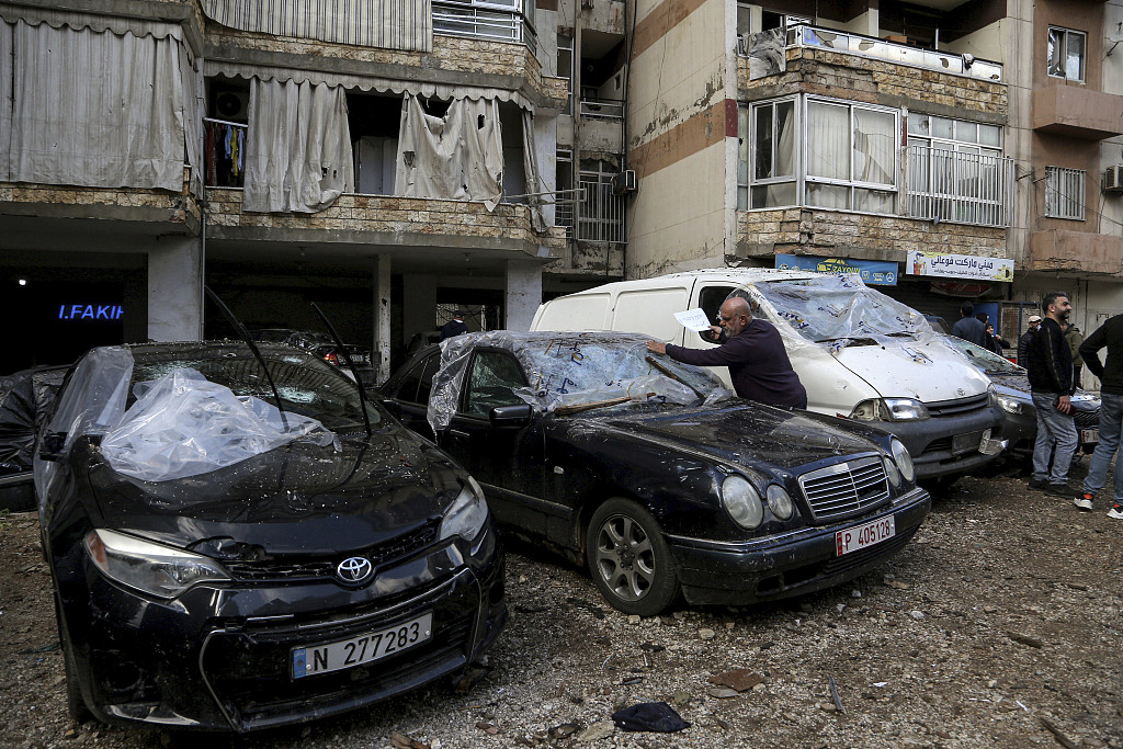 当地时间1月3日,贝鲁特,一名黎巴嫩男子检查被毁的汽车.(视觉中国)