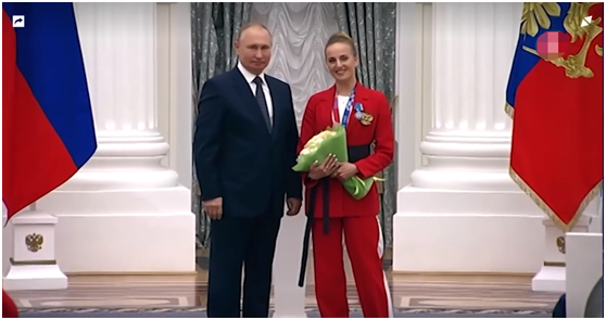 （普京在颁奖仪式上与舒洛奇金娜合影图源：“第五频道”电视台视频截图）