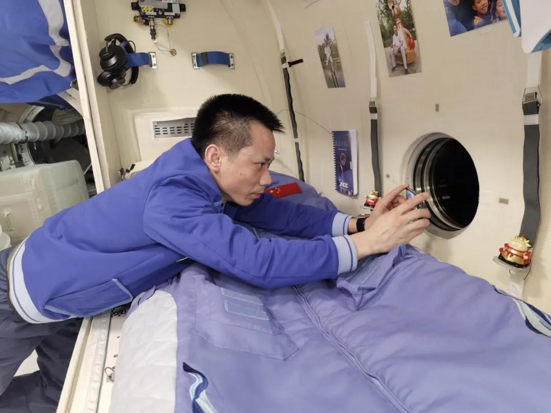 中国航天员汤洪波拿着手机对向窗外拍摄。