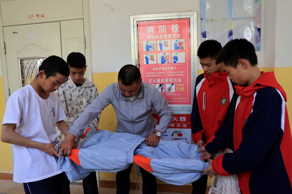 5月13日,在青海省西宁市海湖中学,学生和老师一同制作简易担架.